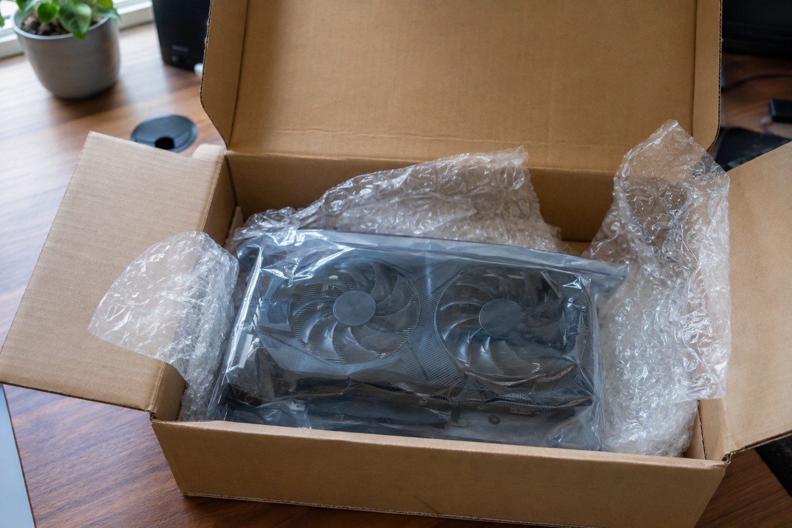 Illustration: an open shipping box on a desk with a used graphics card in an anti-static bag
