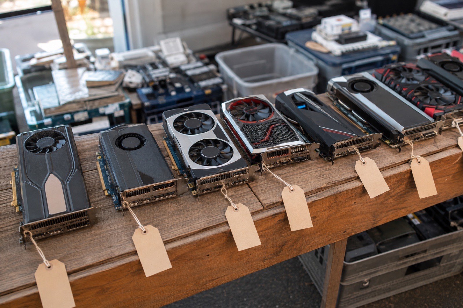 Illustration: a row of used graphics cards from different generations on a wooden table with blank price tags